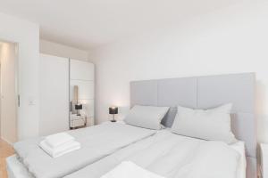 um quarto branco com uma grande cama branca com almofadas brancas em Schöne 2 Zimmer Wohnung zentral in Stuttgart West em Stuttgart