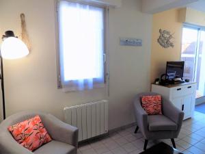 ein Wohnzimmer mit 2 Stühlen und einem TV in der Unterkunft Saint Georges de Didonne - APPARTEMENT COSY avec BALCON - PROCHE PLAGE in Saint-Georges-de-Didonne