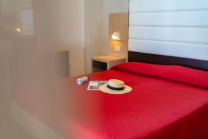 czerwone łóżko z kapeluszem w obiekcie Ciccio Hotel w mieście Misano Adriatico