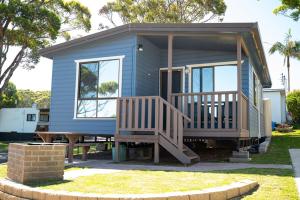 a blue tiny house with a porch and a picnic table at Joalah Holiday Park in Durras
