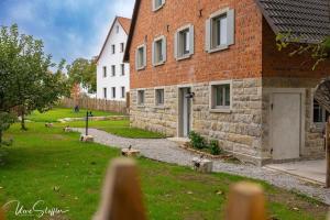 a brick building with a grass yard next to it at Landurlaub mit neugierigen Blicken in den Pferdestall, eingezäuntem Garten, Kamin und Sauna in Rot am See