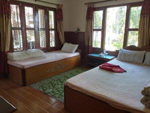 um quarto com 2 camas, janelas e um tapete em Hotel Tree Land em Sauraha