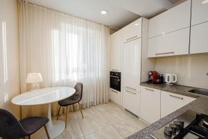 cocina con armarios blancos, mesa y sillas en Comfy apartment in Chisinau!, en Chişinău