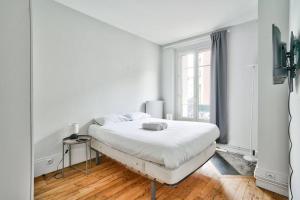 ein weißes Schlafzimmer mit einem Bett und einem Fenster in der Unterkunft Charmant T2 à 5 minute de Paris in Issy-les-Moulineaux