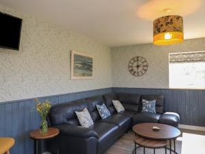 a living room with a leather couch and a table at Eala Bhàn Cottage in Carinish