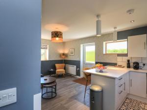 a kitchen and living room with a table and chairs at Eala Bhàn Cottage in Carinish