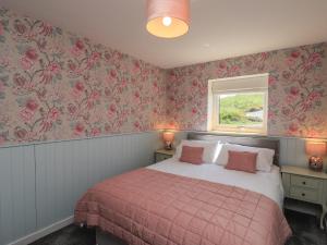 a bedroom with a bed with pink floral wallpaper at Eala Bhàn Cottage in Carinish