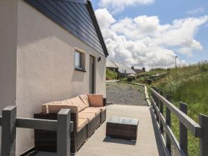 a couch sitting on the side of a building at Eala Bhàn Cottage in Carinish
