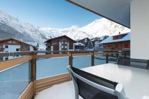 a balcony with a table and a view of mountains at Apartments Auriga in Saas-Fee