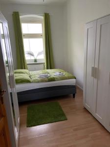 a bedroom with a bed with a window and green curtains at Wohnen in Loriot’s Wasserstadt mit Kamin in Brandenburg an der Havel