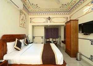 Un dormitorio con una cama grande con un televisor en la pared. en Virasat Mahal Heritage Hotel-Jaipur City Center, en Jaipur