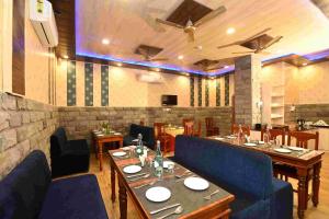Un restaurante con mesas de madera y sillas azules. en Virasat Mahal Heritage Hotel-Jaipur City Center, en Jaipur