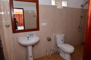 Un baño con inodoro, lavabo y espejo. en Athula Hikka beach Guesthouse, en Hikkaduwa