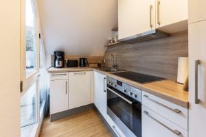 a kitchen with white cabinets and a stove top oven at Karbon in Münster