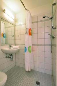 ein Bad mit einem Waschbecken und einem Duschvorhang in der Unterkunft Hotel Petul An der Zeche in Essen