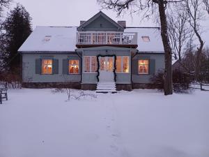 a house with its lights on in the snow at Jūras māja Ausekļi in Kaltene