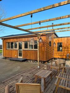 Cabaña de madera con sillas y mesa en la terraza en Magnifique chalet en bord de rivière, en Saint-Avit-les-Guespières