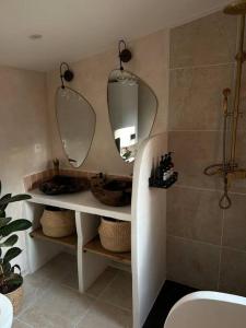 baño con lavabo y 2 espejos en Magnifique chalet en bord de rivière, en Saint-Avit-les-Guespières