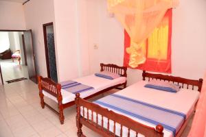 una habitación con dos camas y una ventana en Athula Hikka beach Guesthouse, en Hikkaduwa