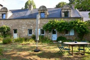 une table et des chaises devant une maison en pierre dans l'établissement KERMANE - Maison 8 personnes Saint-Philibert, à Saint-Philibert