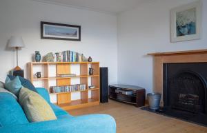 uma sala de estar com um sofá azul e uma lareira em 2 South Duntulm em Kilmaluag