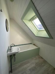 uma casa de banho com um lavatório e uma banheira com uma clarabóia em 2 South Duntulm em Kilmaluag