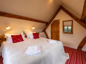 a bedroom with a large white bed with red pillows at The Hayloft in Canterbury
