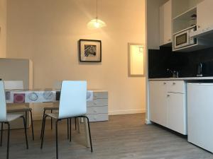 a kitchen with white cabinets and a table and chairs at AparisAppart in Pantin