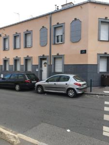 two cars parked in a parking lot in front of a building at AparisAppart in Pantin