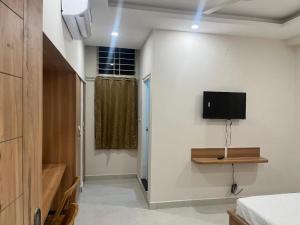 Zimmer mit einem TV an der Wand und einem Schlafzimmer in der Unterkunft Seema Palace Inn in Mysore
