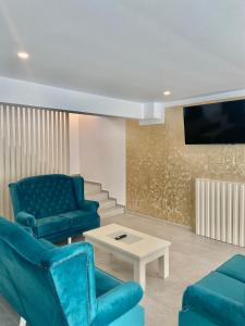 uma sala de estar com cadeiras azuis e uma televisão em Royal Alpin Crown em Cavnic