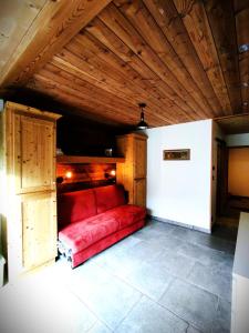 um sofá vermelho num quarto com tecto de madeira em Grand Studio Val Cenis em Lanslebourg-Mont-Cenis