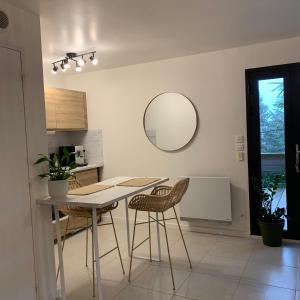 eine Küche mit einem Tisch, Stühlen und einem Spiegel in der Unterkunft Superbe studio tendance et zen proche de Lyon in Couzon-au-Mont-dʼOr