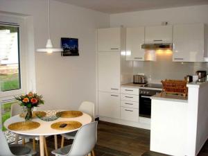 uma cozinha com uma mesa branca, uma mesa e cadeiras em Ferienhaus "Felix" mit freiem Blick em Korswandt