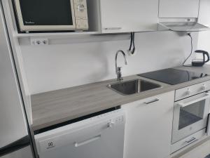 a kitchen with white cabinets and a sink and a microwave at Easy stay in Tampere