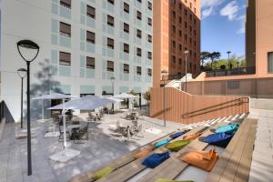 - une piscine avec des chaises et des tables dans un bâtiment dans l'établissement Livensa Living Studios Bilbao, à Bilbao