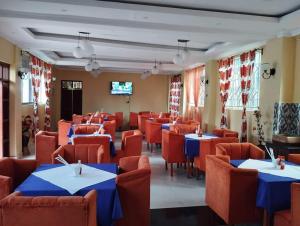 a dining room with blue tables and orange chairs at Villa Martis Kakamega in Kakamega