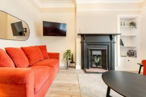 uma sala de estar com um sofá laranja e uma lareira em St Andrews - 5 min walk to centre em St. Andrews