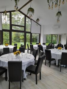 un comedor con mesas y sillas blancas y ventanas en Moara Viselor, en Vaideeni