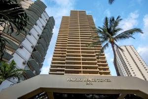 a tall building with a palm tree in front of it at Aston Waikiki Beach Tower in Honolulu