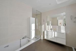 une salle de bain blanche avec une baignoire et un miroir dans l'établissement Le loft des Papes - 2 terrasses - Vue Panoramique sur la ville - AC CLIM, à Avignon