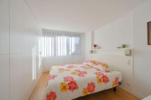 a white bedroom with a bed with flowers on it at Le loft des Papes - Vue Panoramique sur la ville - AC CLIM - 2 terrasses - Hypercentre in Avignon