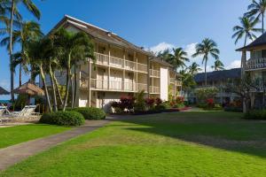 a resort building with palm trees and a lawn at Aston Islander On The Beach in Kapaa