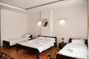 three beds in a room with white walls at Apartmani swiss Gold in Priboj