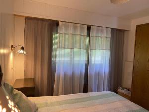 um quarto com uma cama e uma janela com cortinas em La Foret 42 2 bedroom apartment with parking and sauna em Riddes