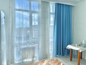 a room with a large window with blue curtains at G-home apartments in Expo New life-2 in Astana