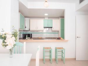 a kitchen with green and white cabinets and a table and chairs at Precioso apartamento en el Calón Playa con vistas y piscina in El Calón