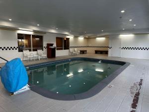 a large swimming pool in a large room with chairs and tables at SureStay Plus by Best Western Fenton in Fenton