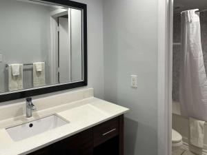 y baño con lavabo, espejo y aseo. en Motel 6 Greenville, NC ECU Medical Center en Greenville