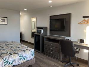 1 dormitorio con 1 cama y escritorio con TV en Motel 6 Greenville, NC ECU Medical Center, en Greenville